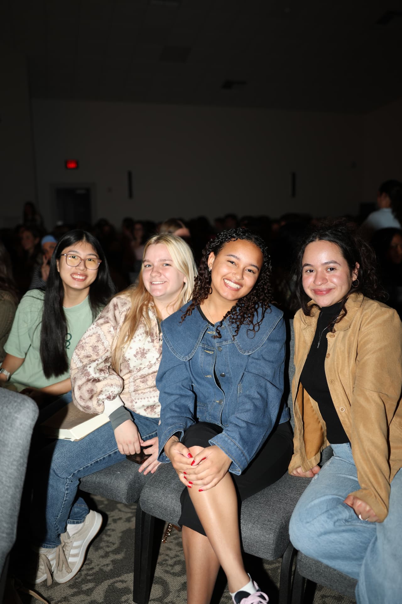 Four students seated together smiling before a gathering